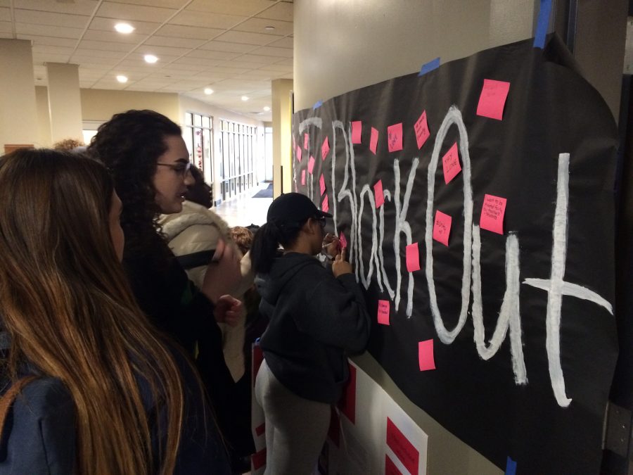 Students place sticky notes with their experiences and feelings about discrimination on a poster in the Campus Center. (Photo by Evan Bourtis)