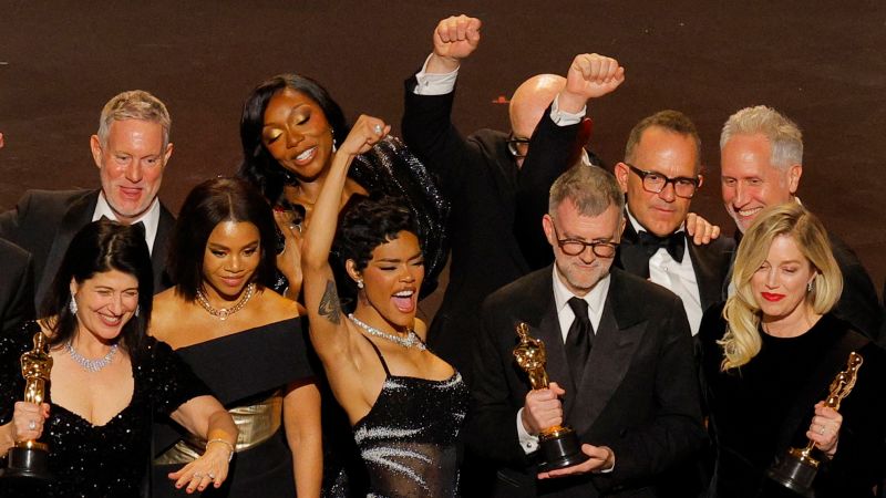 Paul Thomas Anderson and Sara Murphy accept the best picture award for "One Battle After Another" alongside cast and crew during the 2026 Oscars. 